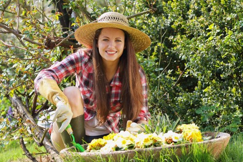 Gardener following safe procedures while pruning a hedge