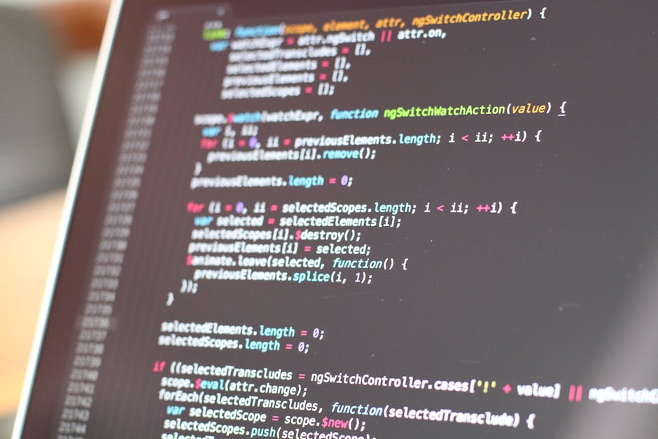 A computer screen displays a close-up of a code editor with multicolored programming code in various lines, featuring syntax highlighting in red, blue, green, and white. The background shows a blurred